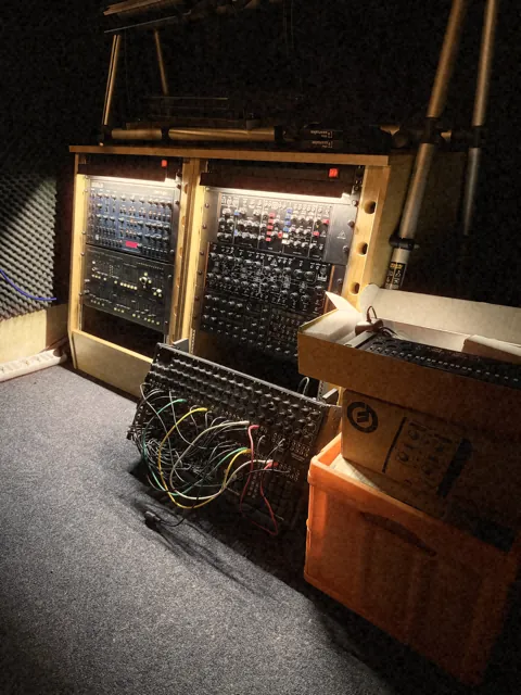 Synthesizer cases with patch cables in the studio corner
