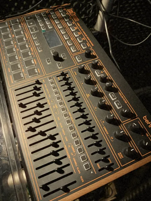 Drum machine with orange faders and wooden side panels